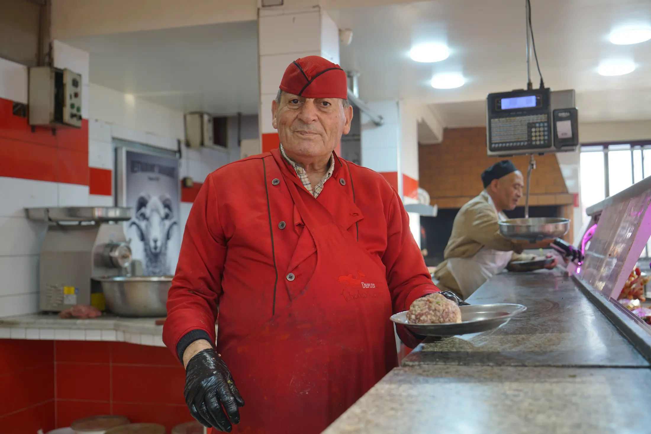 Le boucher derrière sa vitrine